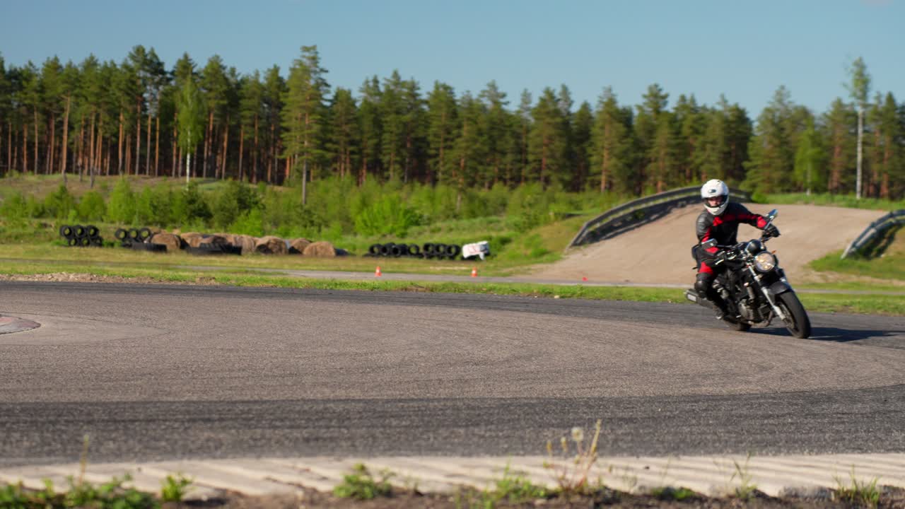 Motociclista su pista di allenamento, che curva a destra al rallentatore.