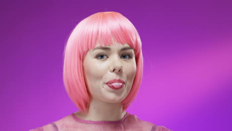 close up of stylish woman wearing a pink wig and glasses and chewing gum 1