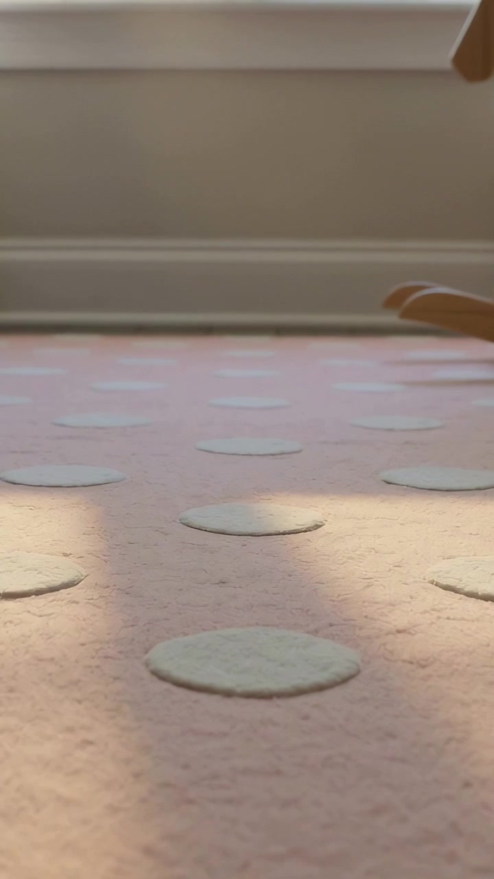 Vertical video: Panning camera showing pink rug with raised dots at home, sun patch and rocker leg