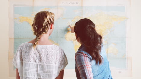 tourist girls looking at world map planning travel adventure