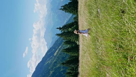 slow motion shot of happy girl in white dress, walking and jumping in green pasture on hill during sunny summer day - tracking shot