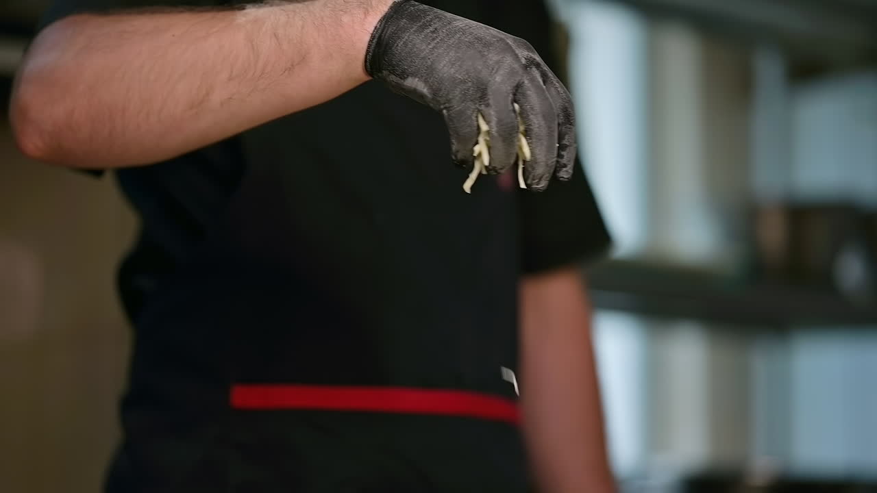 Cooking pizza in a restaurant. The cook pours grated cheese on the raw dough