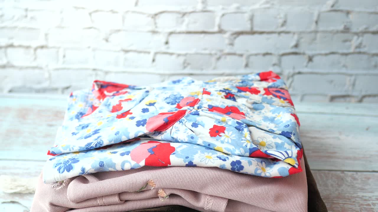 여자 가 어린이 의 옷 을 접고 정리 하고 있다