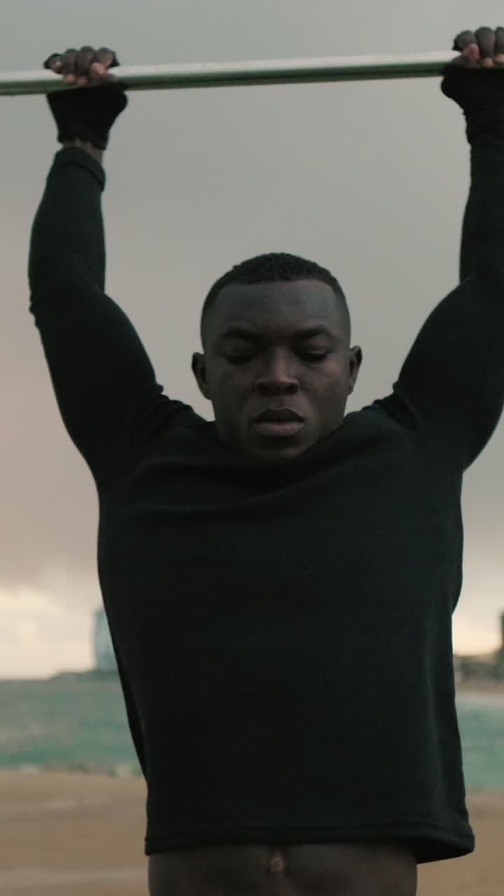 Athletic Young Man Doing Pull-Ups on a Bar by the Ocean