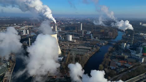 aerial view of a thermal power plant emitting smoke on a sunny day, with a river and a city in the background. nice aerial view flight speed ramp hyper motion time lapse