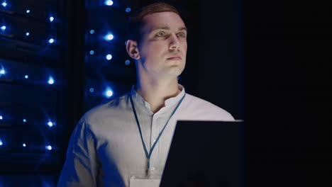 it technician in data center digital server room controlling work of rack server cabinets with a tablet. professional server engineer at work. man technicians working in high tech server rack room