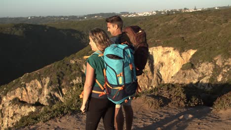 pareja de excursionistas con mochilas de campamento de pie en el acantilado