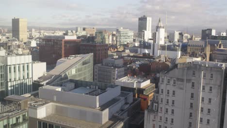 slow pan across manchester city centre, at the heart of its financial district, with a view of the hills at the city's edge in the background.
