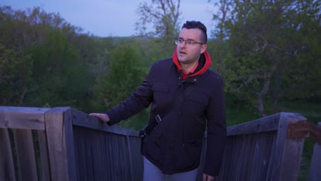 subiendo las escaleras a una plataforma de observación mientras mira a su alrededor alrededor del bosque de robles en la montaña strandzha en bulgaria