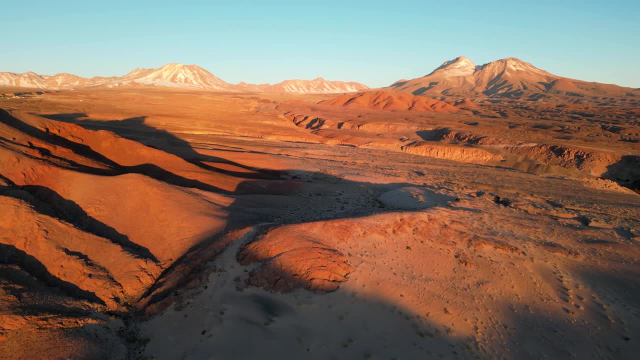 High-altitude drone footage capturing golden light on rugged desert peaks in the Andes
