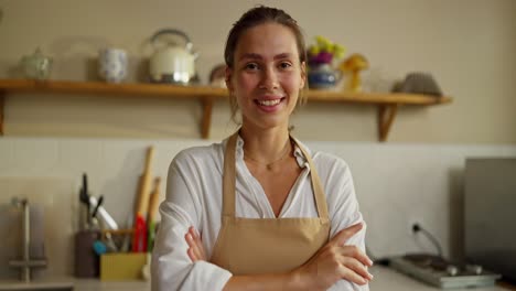 a young woman in an apron smiling in a kitchen