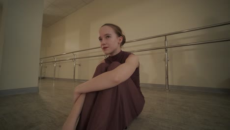 a group of young ballet students in black dancewear practicing positions in a spacious ballet studio with wooden flooring and wall-mounted barres. focused expressions and synchronized movements.