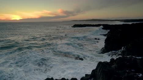 ocean waves crashing on rocky coast in iceland on a golden hour sunset