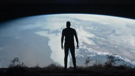 man standing on a hill looking at earth from space