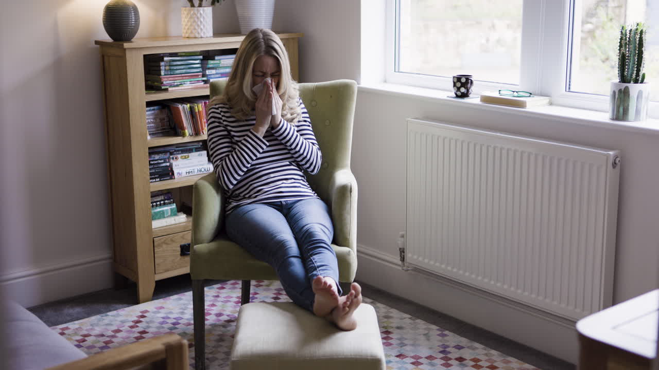 Woman with cold sitting in chair at home