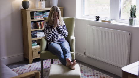 woman with cold sitting in chair at home