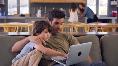 Vater-Und-Sohn-Sitzen-Zusammen-Auf-Dem-Lounge-Sofa-Und-Benutzen-Einen-Laptop