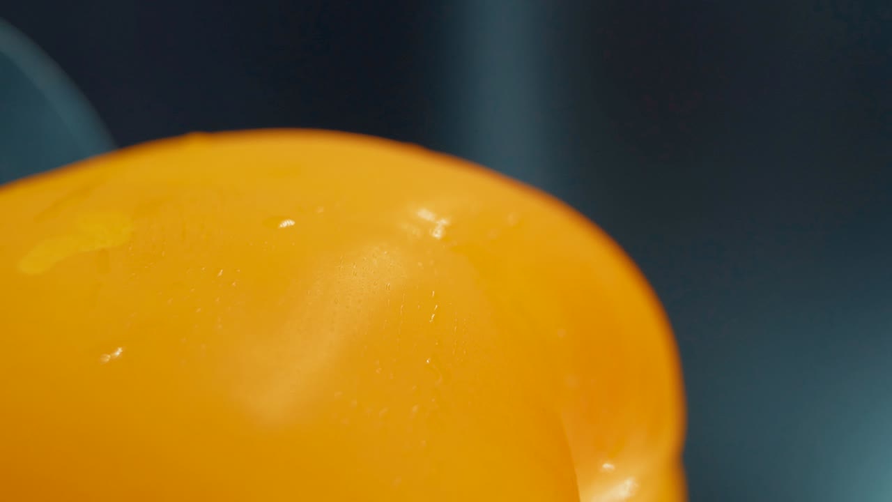 수직 매크로 클로즈업  ⁇ 은 달 ⁇ 한 노란 고추의 자세한  ⁇ , 회전하는 스탠드, 반 ⁇ 이는  ⁇ 이 나는 물방울, 영화 스튜디오 조명, 슈퍼 슬로 모션, 120 fps, 부드러운 움직임, 풀 hd