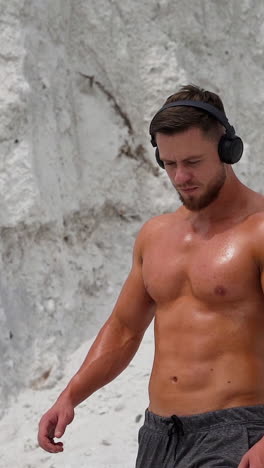 active sport fitness. portrait of muscular man listening music during training on nature vertical video