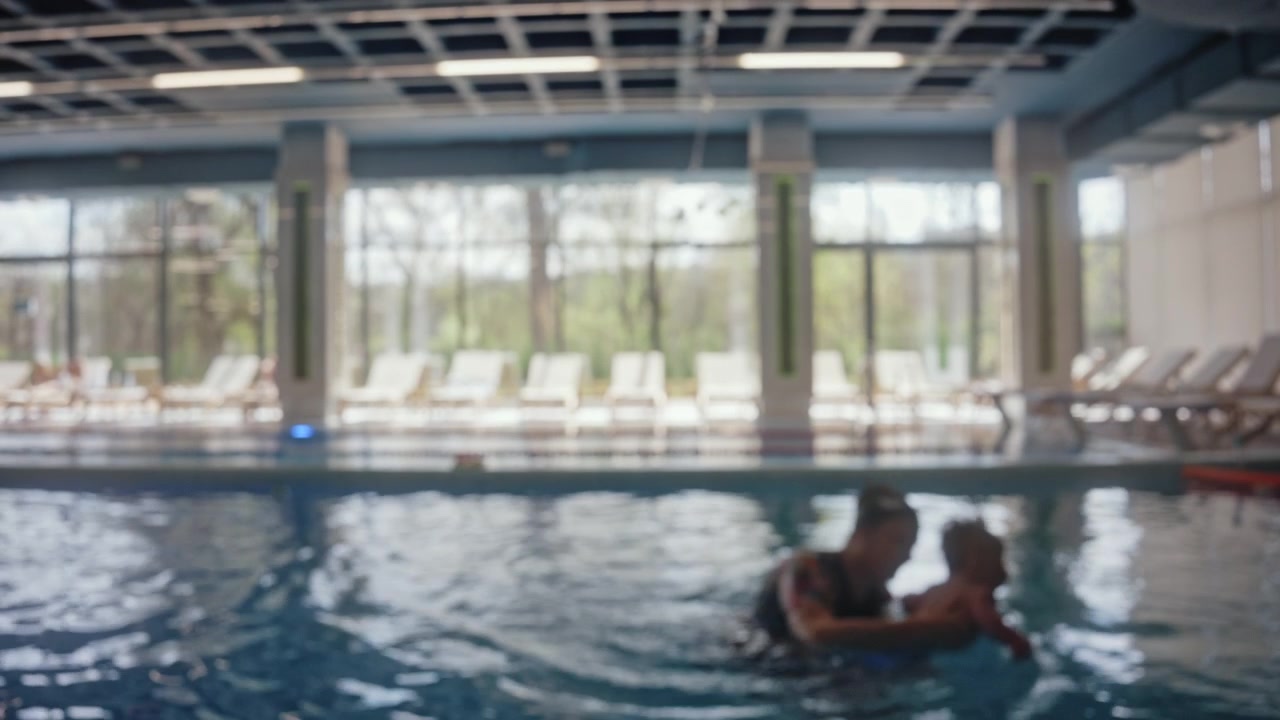 Blurred view of children swimming assisted by instructors during swimming lessons