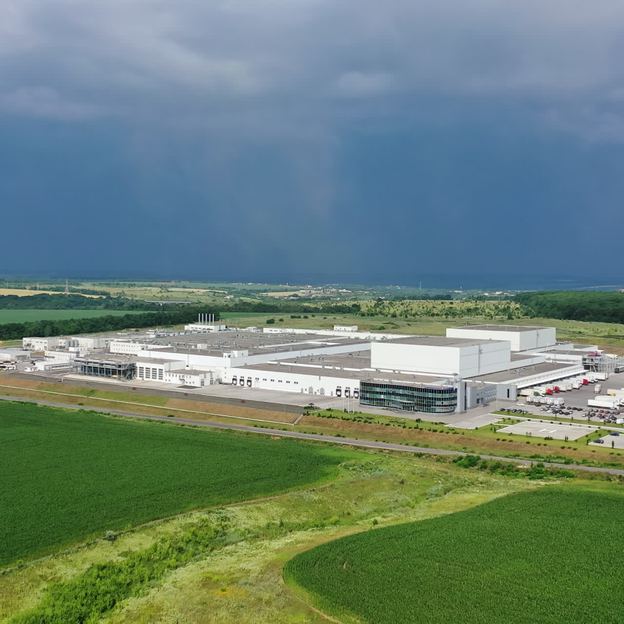 Contemporary industrial complex on beautiful nature background. Huge territory of modern business company in the countryside. Motion camera back.