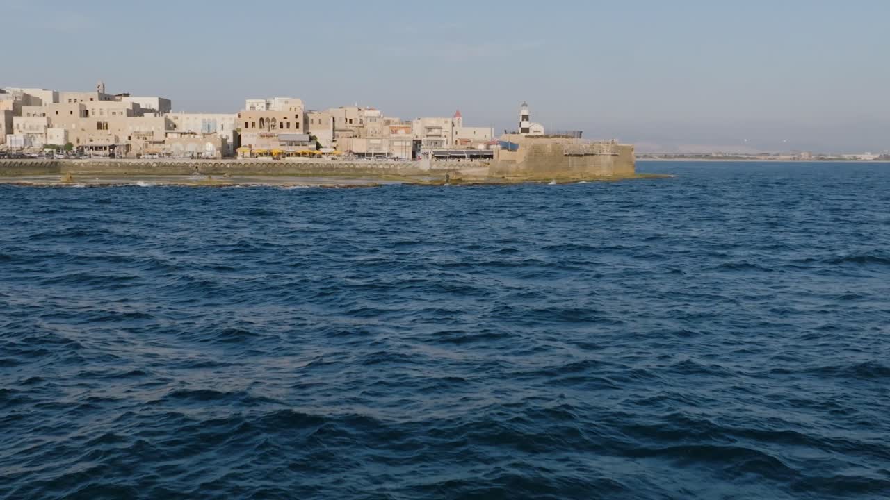 이스라엘 아크레 해안 에서 한 어부 에게 초점을 맞추기 위해 바다 의 파도 위 를 날아다니는 느린 움직임 의 항공 영상