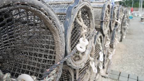 fishing harbour group of stacked lobster pots on coastal marine waterfront dolly left close up