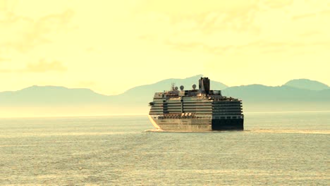 Cruise-ship-sailing-into-the-sunset-with-mountains-along-the-shoreline