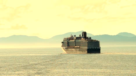 cruise ship sailing into the sunset with mountains along the shoreline