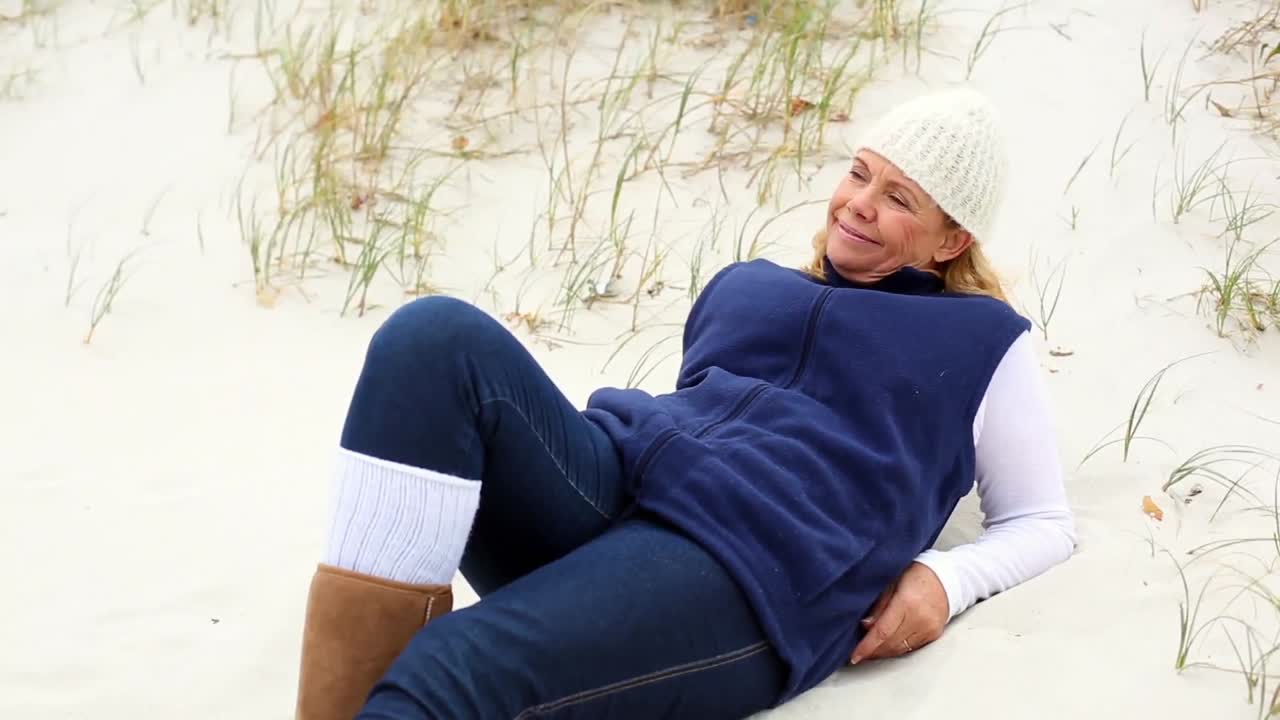 해변에서 휴식을 취하는 행복한 은퇴한 여성