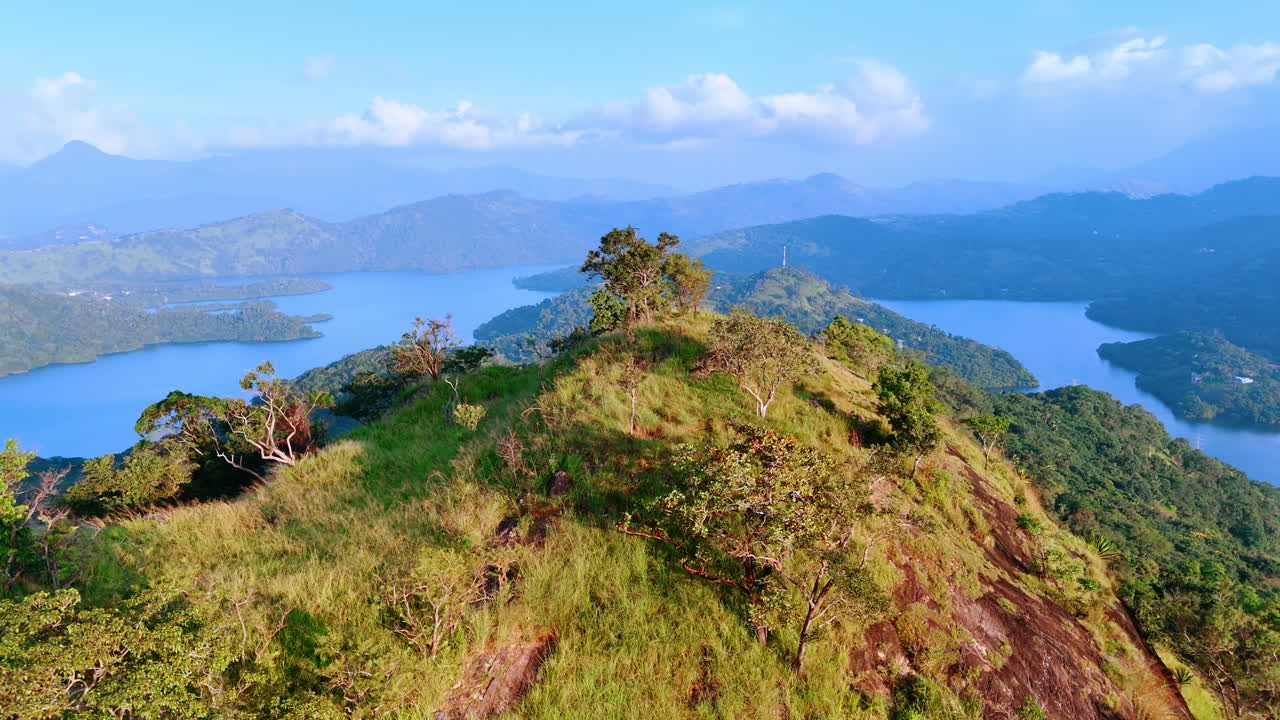Panning footage around the picturesque mountain top covered with green grass. Stunning rocks with waterscape at the foot at backdrop in fog. Top view.