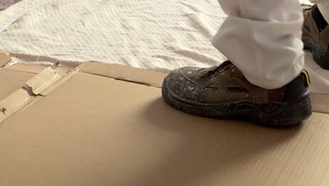 persona está caminando sobre material de caja de cartón prefabricado, pintando las paredes, artesano haciendo concepto de mantenimiento y reparación de la casa interior