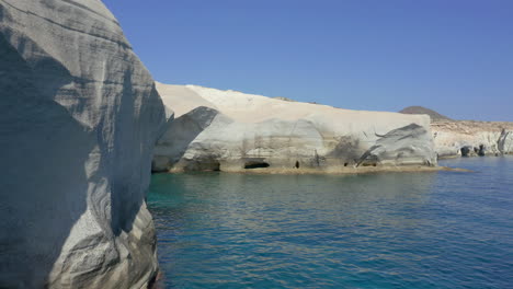 aerial: flying low next to the cliffs on the sarakiniko beach of milos island, cyclades, greece