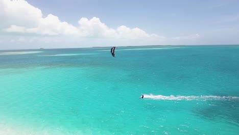 aerial tracking shot man kitesurf in the middle of nowhere, blue ocean