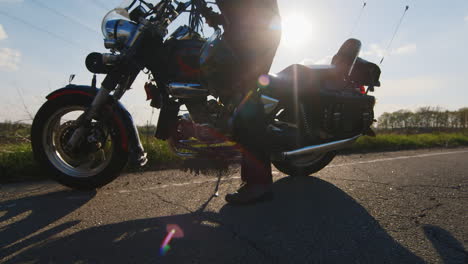 Biker-Sitzen-Auf-Einem-Motorrad-Und-Trägt-Einen-Helm,-Die-Sonnenstrahlen-Scheinen-In-Die-Kamera-Und-Geben-Schöne-R