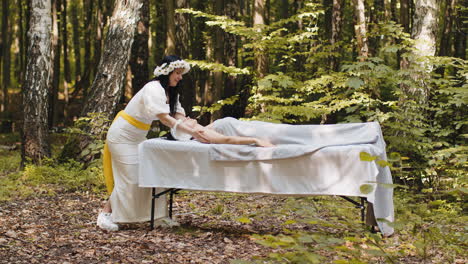 terapeuta mujer médico haciendo mujer relajante spa masaje facial con las manos al aire libre en el bosque