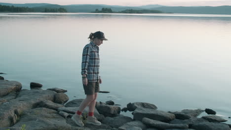 Woman-Walking-on-Rocky-Lakeshore-at-Sunset