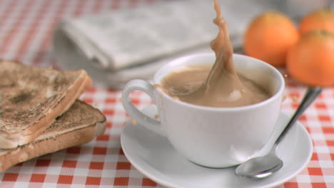 un grumo di zucchero in super rallentatore che cade in una tazza di caffè