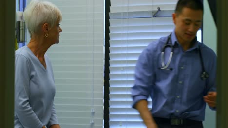 un joven médico asiático y un paciente mayor interactuando entre sí en la clínica 4k