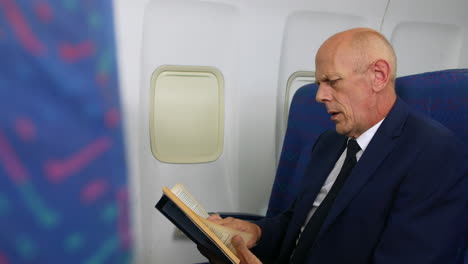 a mature businessman reading a book on an airliner airplane