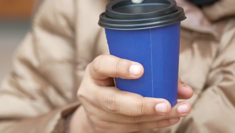 person holding a blue paper coffee cup