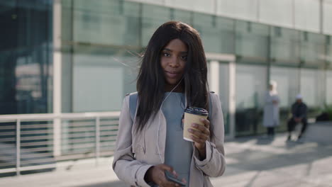 Retrato-De-Una-Hermosa-Mujer-Afroamericana-Mirando-Usando-Un-Teléfono-Inteligente-Sosteniendo-Café