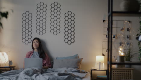 mujer trabajando en la computadora portátil en la cama por la noche