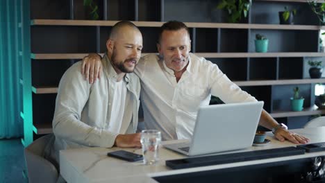 Two-motivated-businessmen-use-laptop-for-video-call-with-colleagues.-Modern-discussion-of-cases,-online-conference