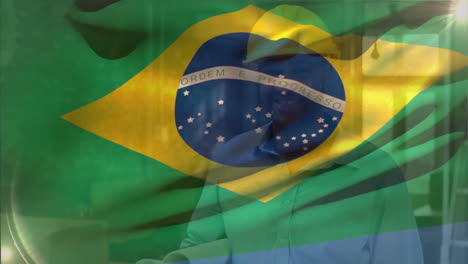 animation of flag of brazil waving, biracial engineer wearing helmet walking with blueprints