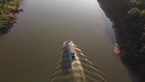 tourist boat sailing on iguazu river at sunset, border between argentina and brazil