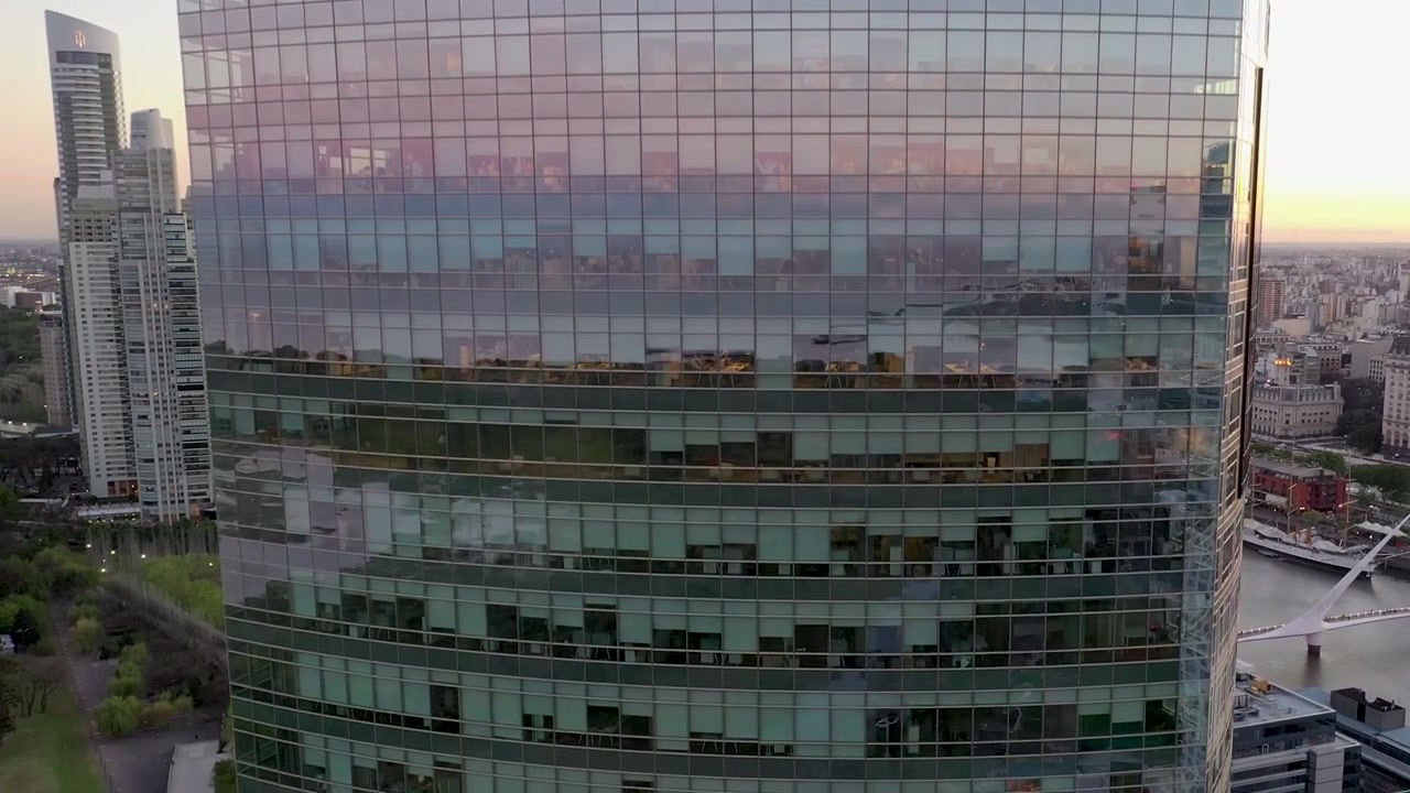 Edifício comercial grande, moderno, luminoso e envidraçado, com muitos escritórios com as luzes acesas. Imagens aéreas de drone 4K ao nascer do sol. Conceito de trabalho e negócios.