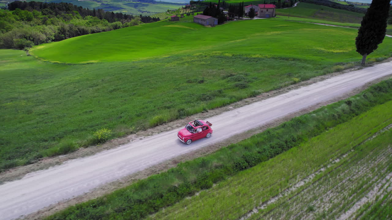 초록색 토스카니아 풍경의 시골 도로에서 빨간 차를 운전하는 항공