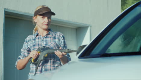 young woman washing her car near the backyard garage of the house