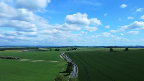 Aerial-view-of-traffic-on-rural-countryside-road-amidst-green-fields-in-England